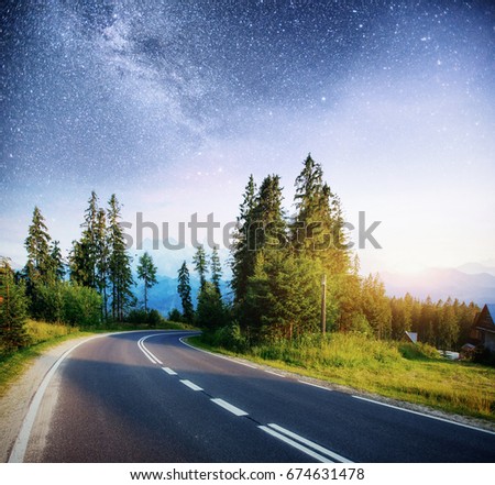 Asphalt road under a starry night sky and the Milky Way.