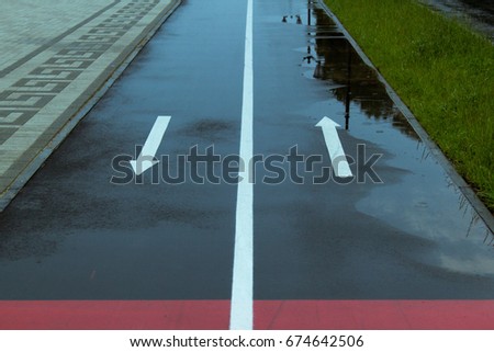 Two arrows forwards and backwards on wet asphalt, bicycle path.