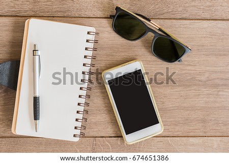 notebook paper and pen with mobile phone on wood table,top view