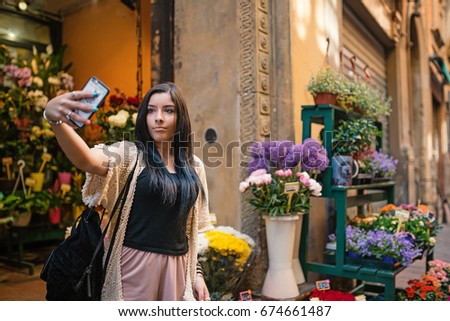 Brunette teenager portrait taking selfie outdoors in the narrow streets of Bologna, Italy.