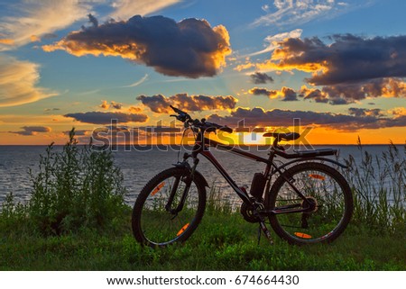 The bike on the coast of the river in the sunset