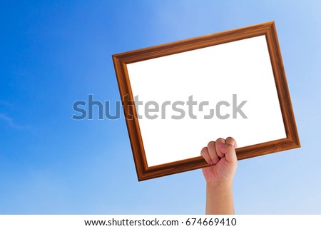 Hand holding wooden frame on blue sky background, announcement concept