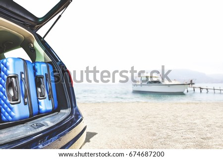Blue car with open trunk and few suitcase and summer background of beach sea and white yacht. Photo with free space for your decoration. 