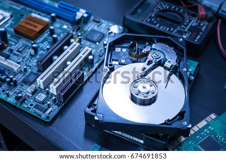 The abstract image of inside of hard disk drive on the technician's desk and a computer motherboard as a component. the concept of data, hardware, and information technology. Royalty-Free Stock Photo #674691853
