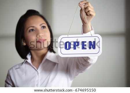Woman hanging Open sign in doorway