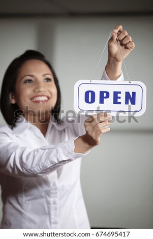 Woman hanging Open sign at the door