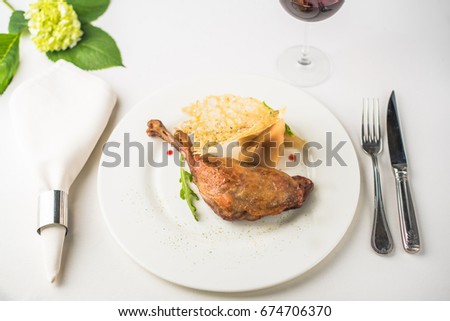 Goose-foot, potatoes and a glass of wine close-up of a decorated table on a white background. Healthy fresh food.