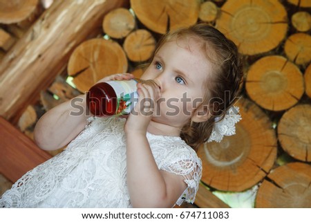 Asian little girl drinks juice from a bottle.