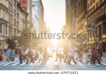 Anonymous group of people walking across a pedestrian crosswalk on a New York City street with a glowing sunset light shining in the background Royalty-Free Stock Photo #674711821