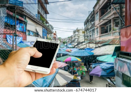 Man use mobile phone, blur image of street market as background.