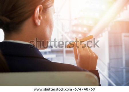 Businesswoman holding cigar against modern stairs in office building