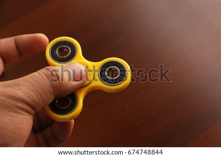 A hand tries to spin a Fidget Spinner which is a useless machine but became a popular recreational toy for people who wanted to cut boredom and relieve stress.
