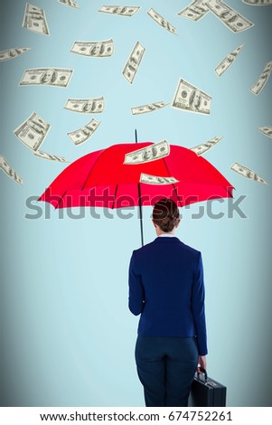 Full length rear view of businesswoman carrying red umbrella and briefcase against blue background