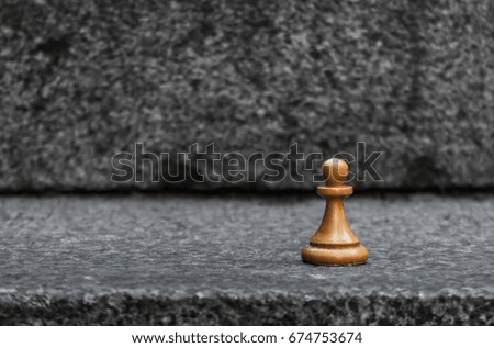 A lone wooden pawn on a concrete wall. Business concept.