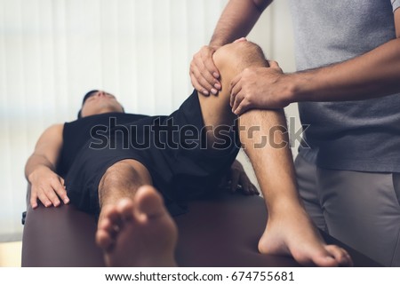 Male therapist massaging knee of athlete patient - sport physical therapy concept Royalty-Free Stock Photo #674755681