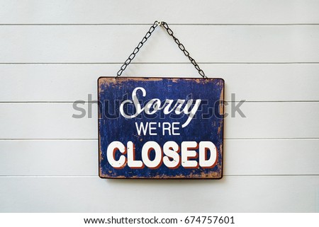 text "sorry we're closed" on rusty metal plate hanging on white wall Royalty-Free Stock Photo #674757601