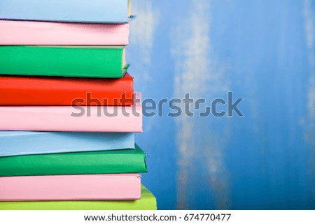 Stack of books on a blue background. A lot of books are close-up.