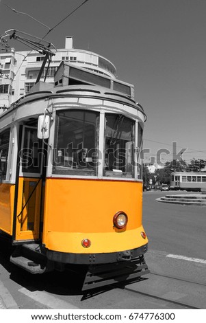 Black and white picture with colored Lisbon yellow tram close up at tram stop. Famous portuguese tourist attraction retro vintage style public transportation in the city. Sunny summer scene background