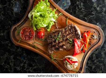 Juicy steak fillet mignon made from marbled beef with baked vegetables on a wooden board