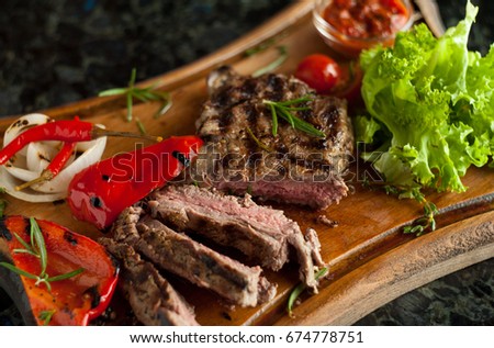 Juicy sliced steak fillet mignon made from marbled beef with baked vegetables on a wooden board