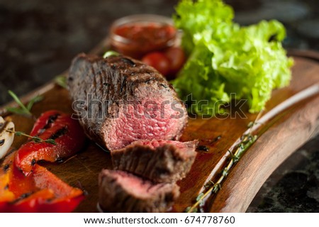 Juicy chopped steak chateaubriand of marbled beef with baked vegetables on a wooden board
