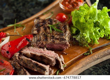 Juicy sliced steak fillet mignon made from marbled beef with baked vegetables on a wooden board