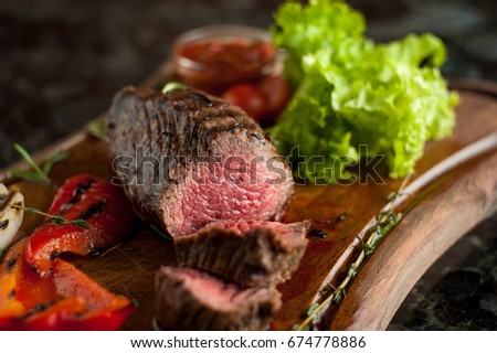 Juicy chopped steak chateaubriand of marbled beef with baked vegetables on a wooden board