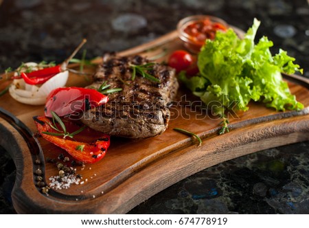Juicy steak fillet mignon made from marbled beef with baked vegetables on a wooden board