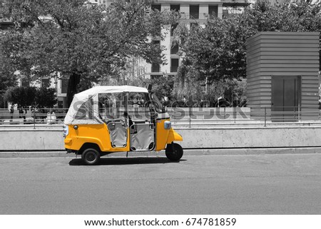 Tuk tuk small passenger three wheel mini car isolated on summer empty city center street road view. Black and white photography pattern selective color picture texture with empty copy space background