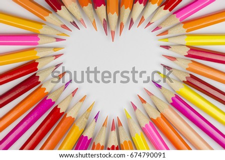 Collection of colored pencils in heart shape in top view as background picture
