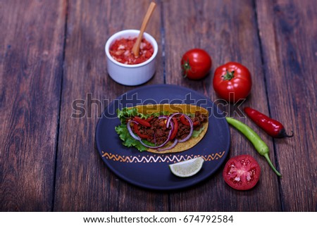 Yummy hot national spicy meal with different colorful ingredients lying on plate near to ripe tomatoes, chili peppers and salsa sauce.
