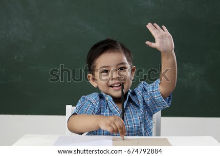 malay boy in the classroom raising arm