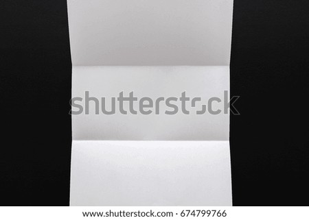 White folded sheet of paper on black background. Abstract backdrop, art, origami concept, copy space
