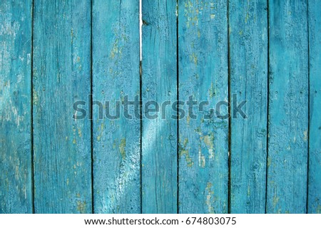 Old fence. A bright summer photo of an old fence, painted with irradiated turquoise paint. Texture of old paint. Craquelure.           