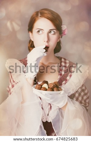 photo of beautiful young woman in vintage dress with plate full of chocolates
