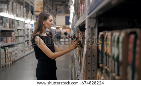 Young woman choosing a bottle of fruits juice at supermarket, young mom mother in shop