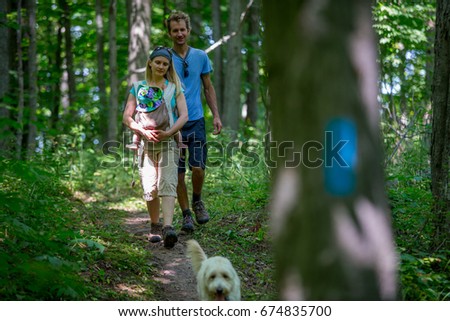 A young family hiking with their dog and their newborn in the forest