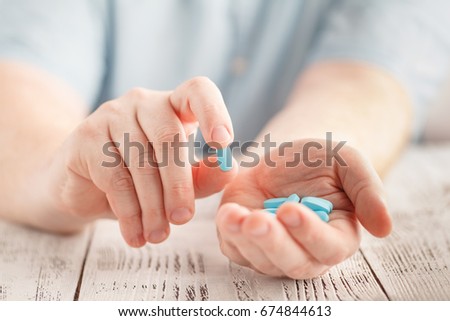 Male hand holding blue pills in palm Royalty-Free Stock Photo #674844613