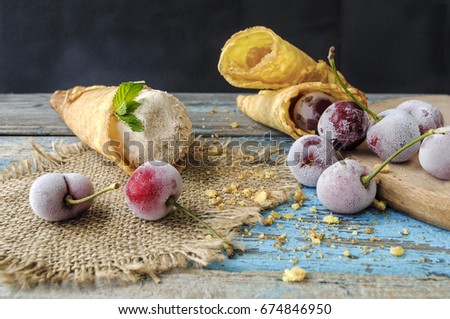 Wafer horn with ice cream and frozen berries on a wooden surface