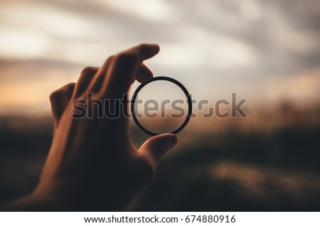 man's hand is holding an optical ring out of focus city Royalty-Free Stock Photo #674880916