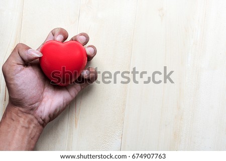 red  pillow heart in hand with on wood table