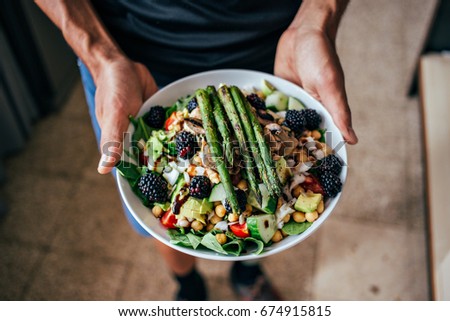 Man hands holding big deep plate full of healthy paleo vegetarian salad made from fresh organic biological ingredients, vegetables and fruits, berries and other nutritional things Royalty-Free Stock Photo #674915815