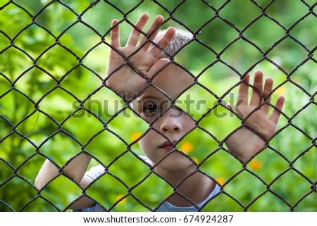 Abstract picture of a little boy behind chain link fence. Photo combination concept
