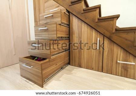 Modern architecture interior with  luxury hallway with glossy wooden stairs in modern storey house. Custom built pullout cabinets on glides in slots under stairs. Use of space for storage. Royalty-Free Stock Photo #674926051