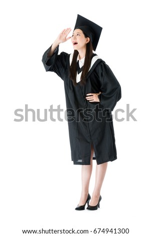 attractive young female college student finished studying wearing graduation clothing standing on white background and looking at distance thinking future plan.