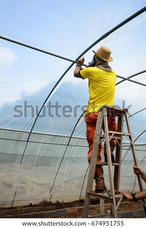 a man repair greenhouse Royalty-Free Stock Photo #674951755