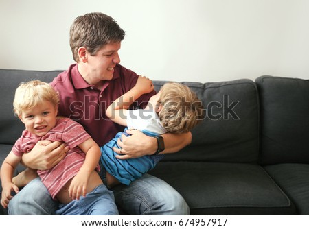 Dad wrestles with sons on the couch