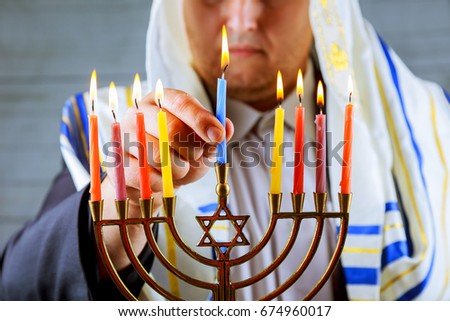 man hand lighting candles in menorah on table served for Hanukkah