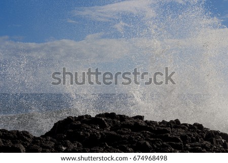 Spectacular backwash from the  Indian Ocean waves breaking on basalt rocks at  Ocean Beach Bunbury Western Australia on a sunny morning in mid-winter  sends salty spray high into the air.