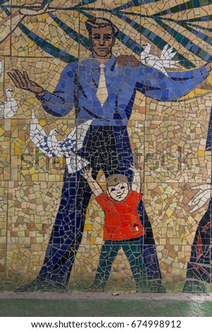 Detail of old antique mosaic with colored glass on wall of destroyed building built in 1947 in USSR. typical plot of street art of USSR period. Mass street culture of primitive Soviet poster. Mosaic